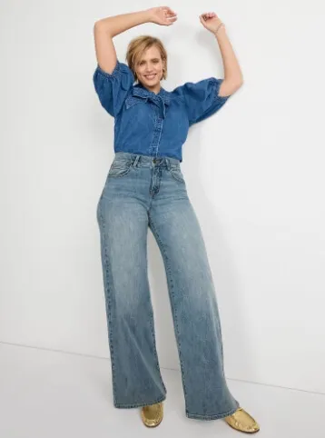 Woman wearing a dark denim top and wide leg denim jeans.