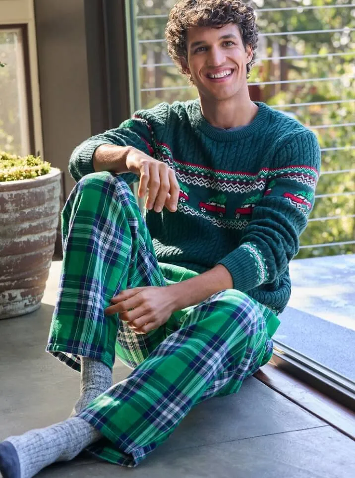 Man wearing a green holiday sweater and green and blue plaid pajama pants.