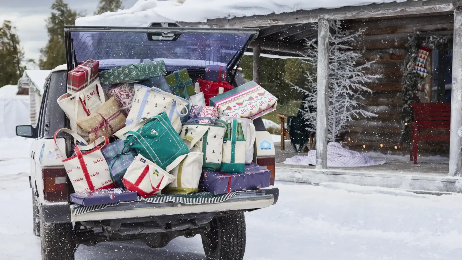 Christmas gifts and Lands' End tote bags overflowing out the back of an SUV parked in front of a snow-covered log cabin.