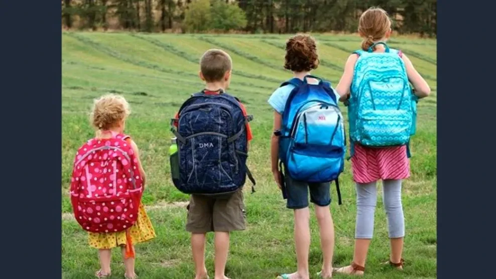 Four kids standing smallest to largest, facing away, wearing Lands' End backpacks.