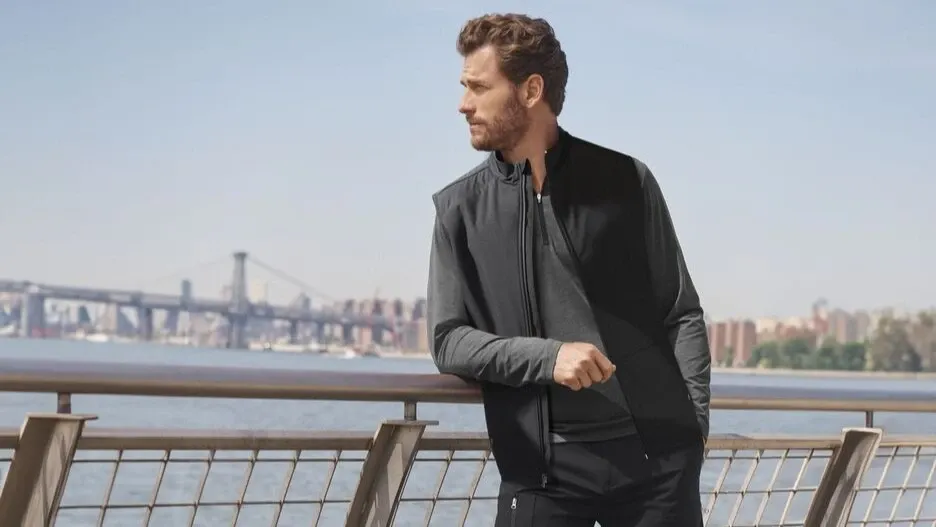 Man wearing a charcoal colored quarter zip under a black vest.