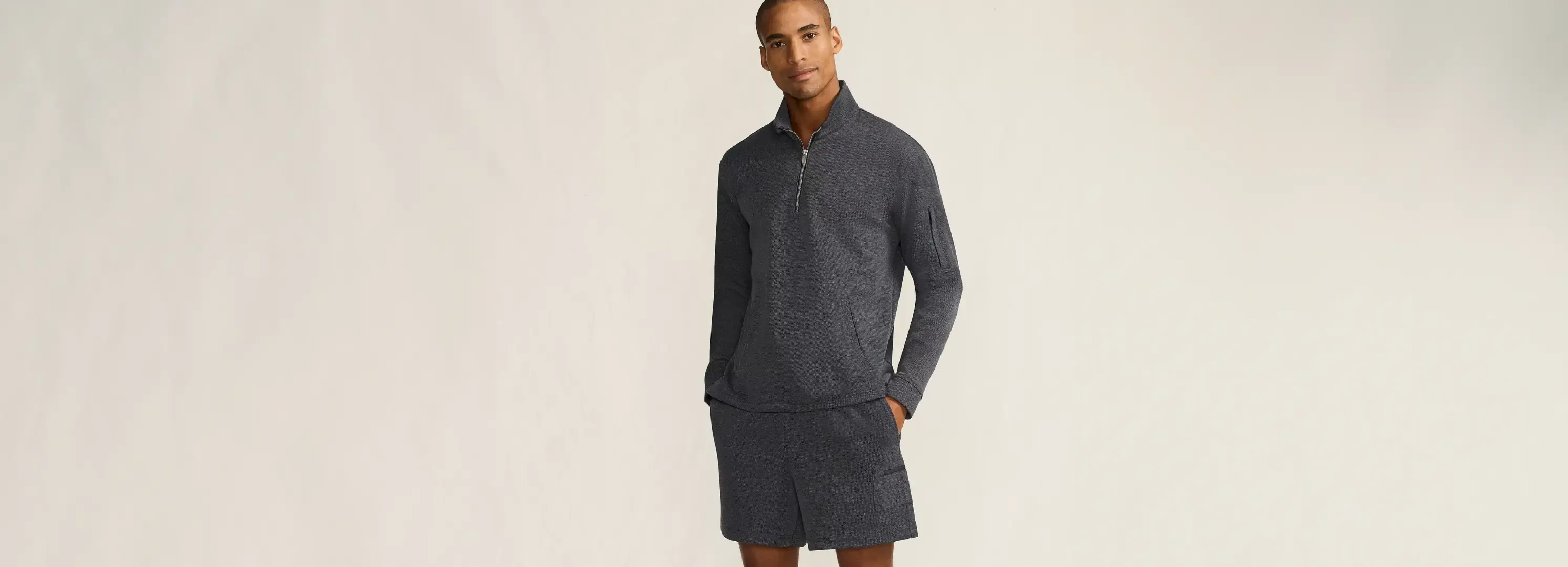 Man wearing a charcoal performance quarter-zip pullover and matching shorts.