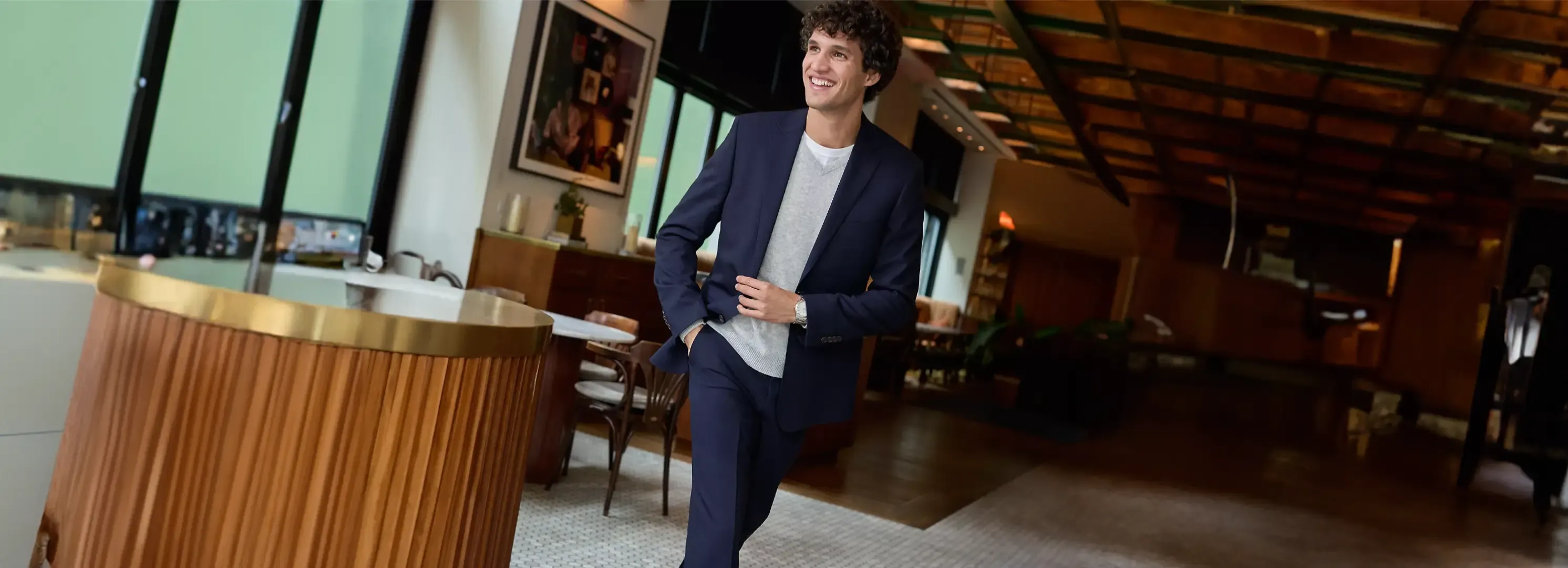 Man wearing a navy blue two-piece suit with a gray v-neck shirt.