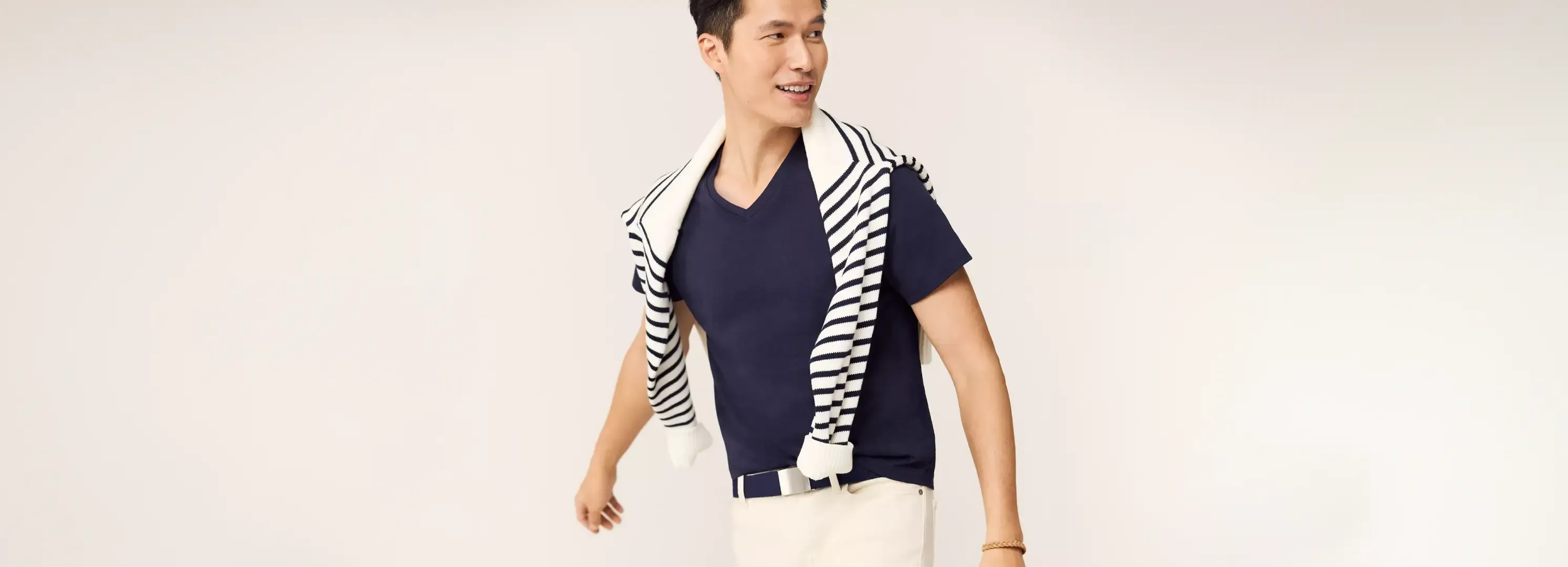 Man wearing a navy t-shirt and a striped sweater over his shoulders.