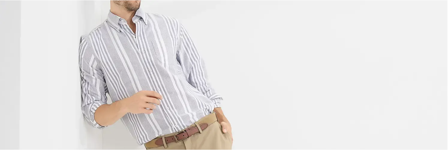Man wearing a light grey and white vertical striped dress shirt with tan no-iron dress pants and brown belt.