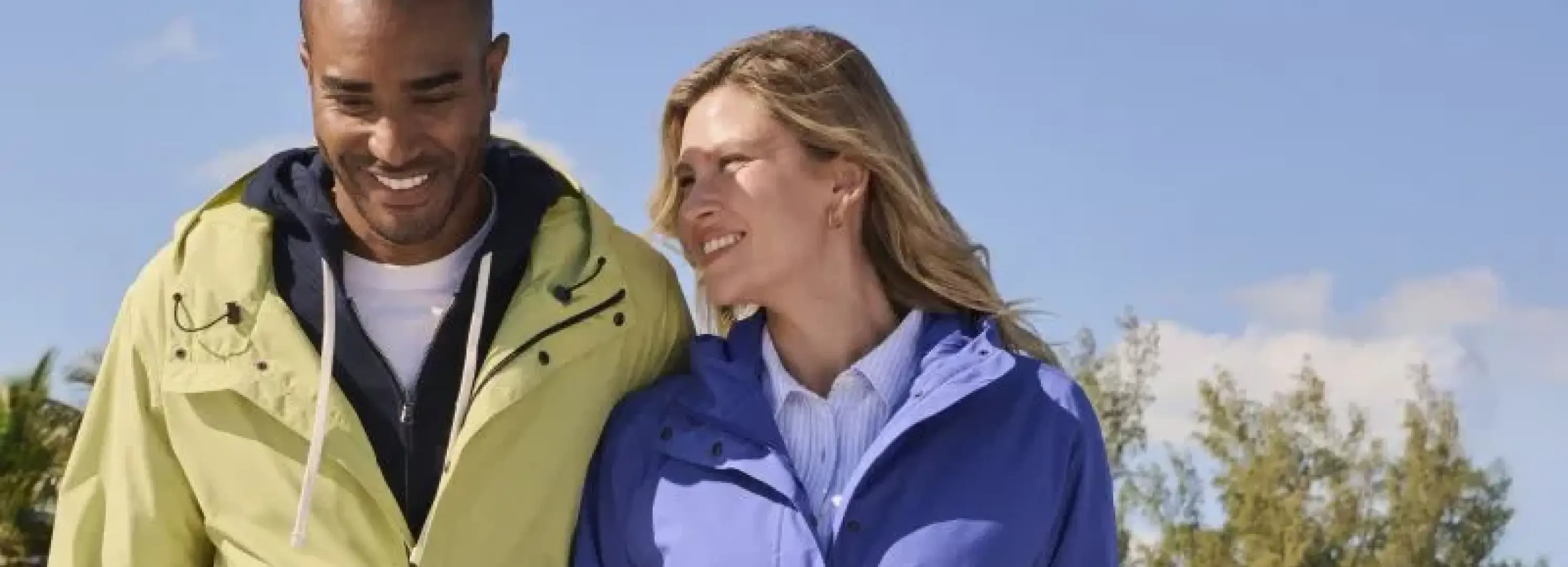 Man wearing a yellow raincoat next to a woman in a blue raincoat.