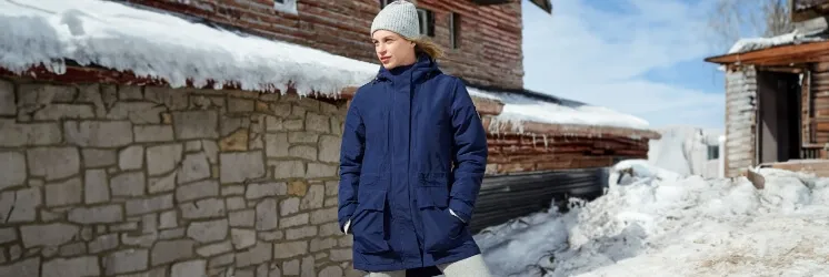 Woman wearing a navy blue parka and gray stocking cap, outside on a winter day.