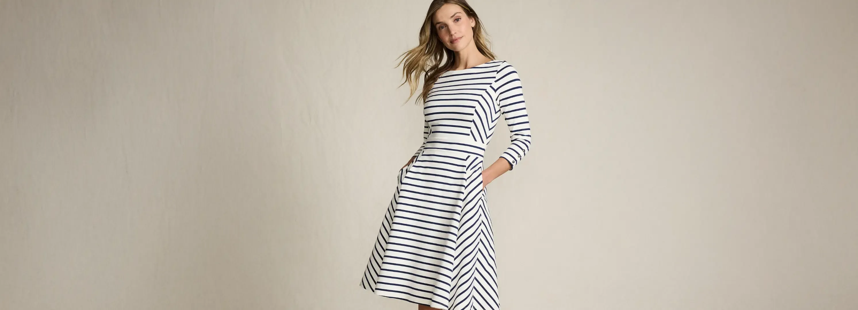 Smiling woman in navy striped fit-and-flare dress with pockets, studio.