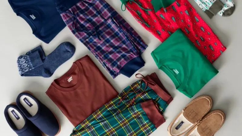 Several sets of seasonal Lands' End pajamas, socks and slippers folded neatly on the ground. 