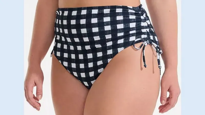 Woman wearing plus size white and navy high-waist bikini bottoms.