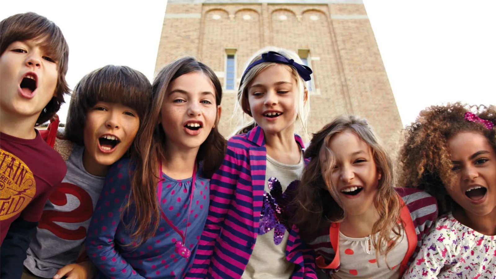 Six kids dressed in Lands' End kids' clothing outside a school.