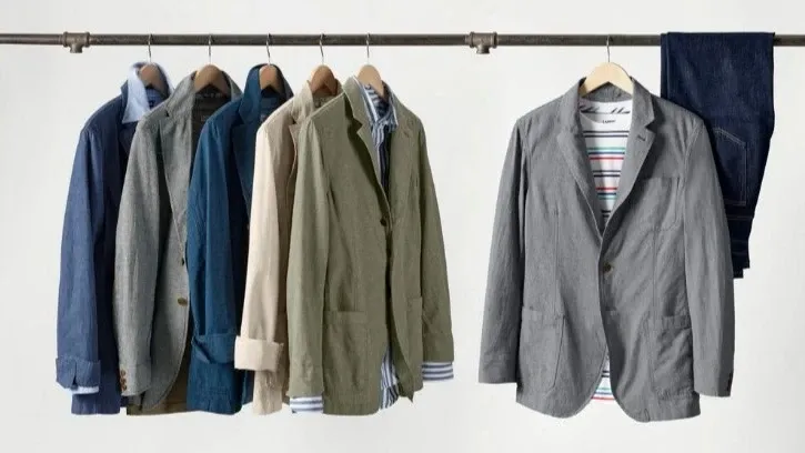 Six Lands' End sport coats and a pair of dark blue jeans hanging from a hanging rod.