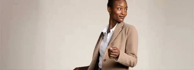 Woman wearing a beige blazer and a white button-down shirt.