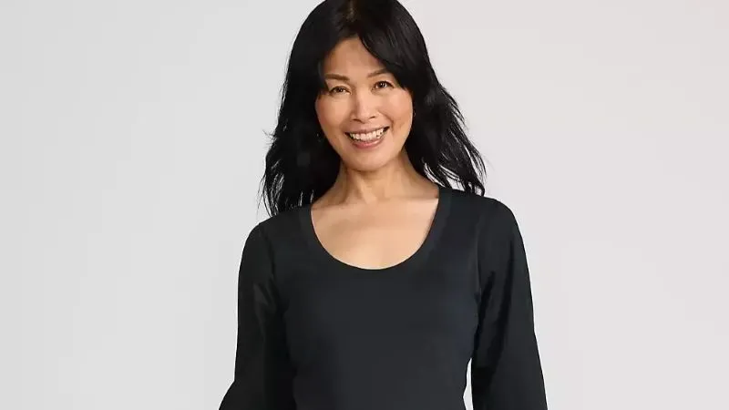 Woman wearing a black scoop neck blouse.