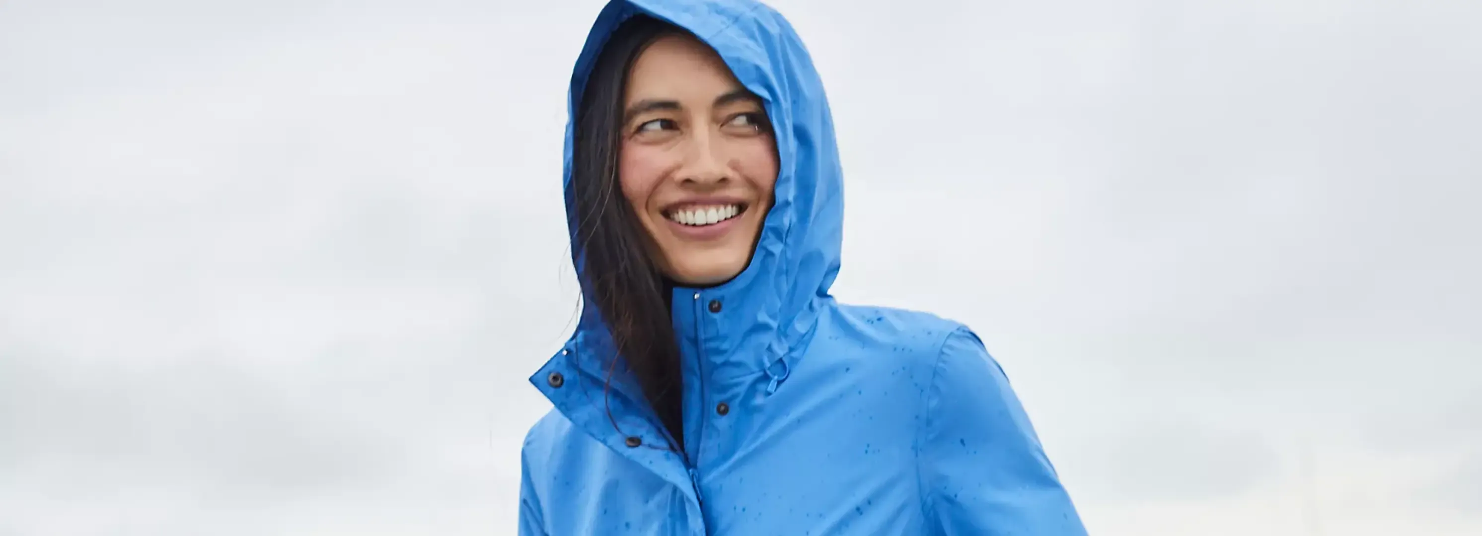 Woman wearing a blue rain jacket with a hood.