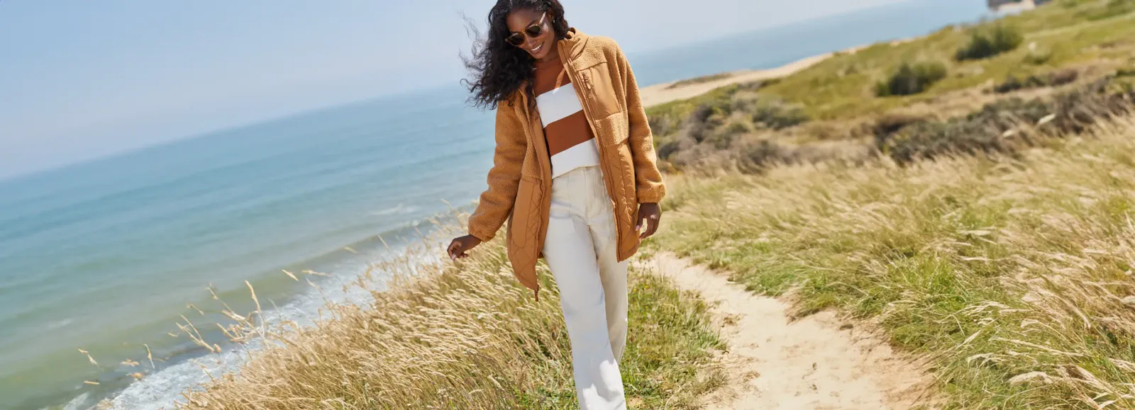 Woman wearing a brown jacket and white pants.
