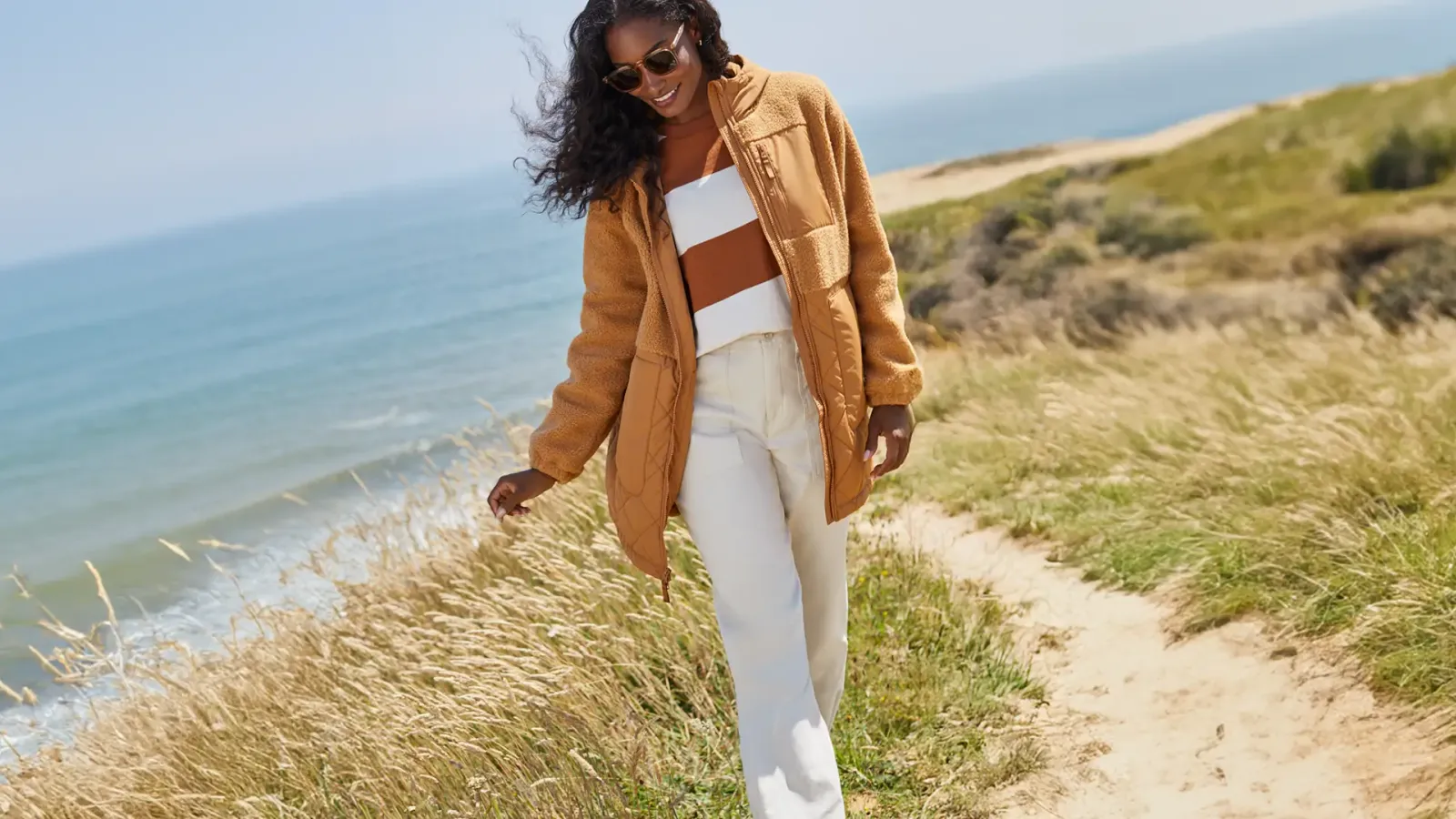Woman wearing a brown jacket and white pants.
