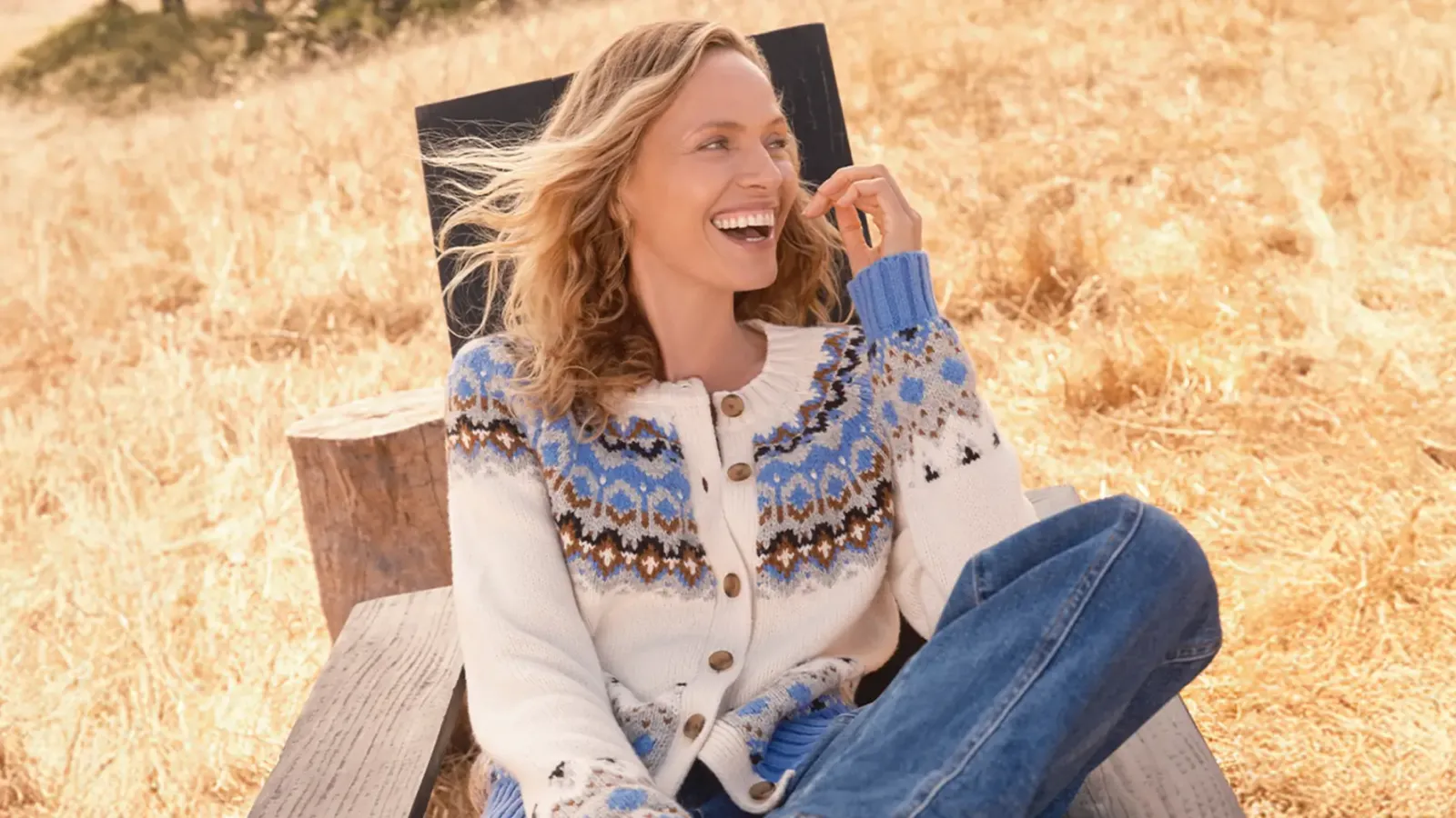 Woman in white and blue pattern cardigan sitting outdoors.