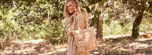Woman holding a desert tan Wanderweight packable tote bag.