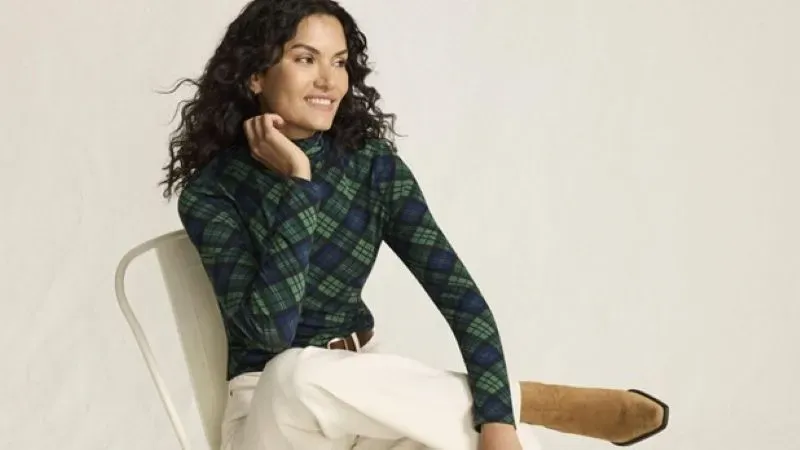Woman wearing a green plaid turtleneck, white pants and tan boots.