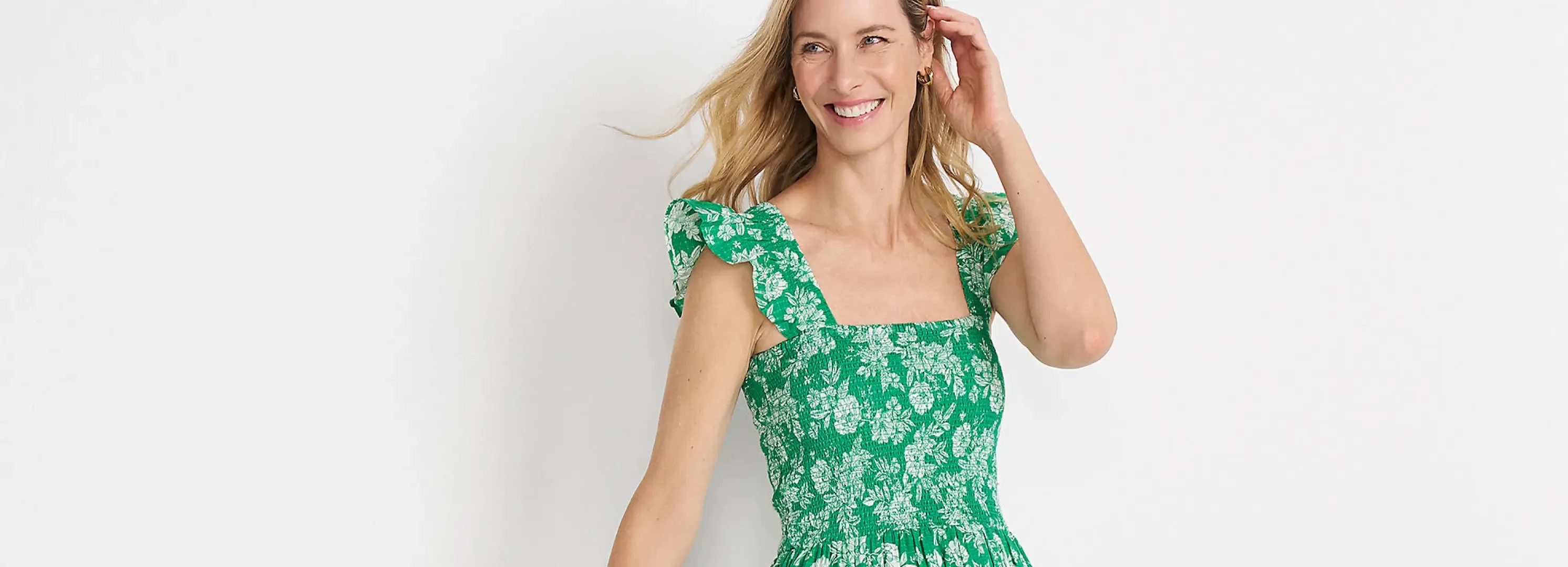 Woman wearing a green smocked dress with ruffle straps.