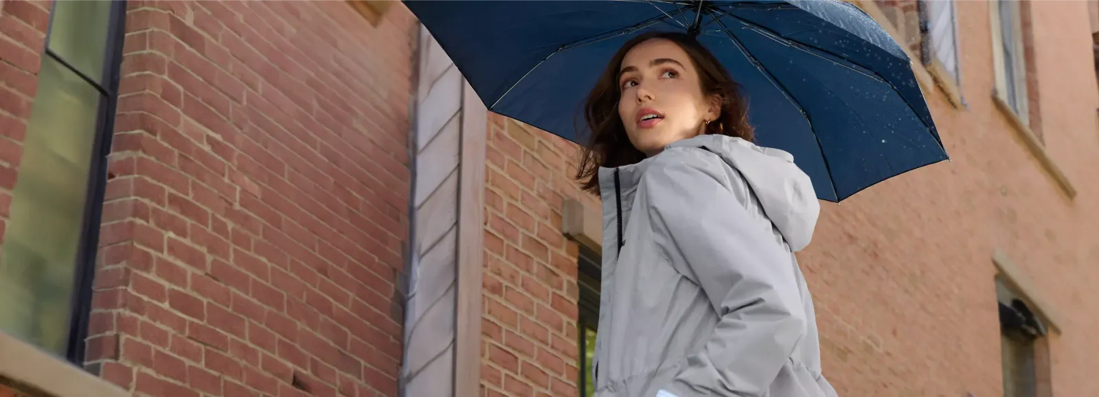 Woman wearing a grey coat holding a blue umbrella.