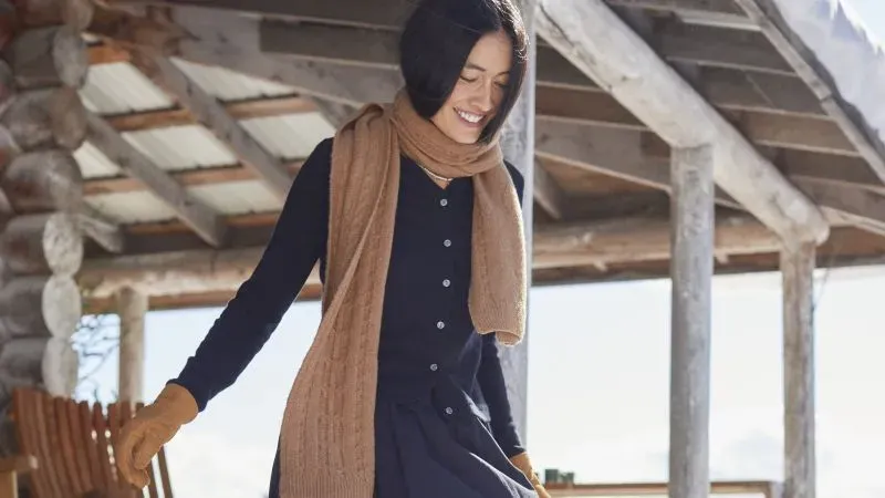 Woman wearing a navy-blue cardigan and matching brown scarf and gloves.