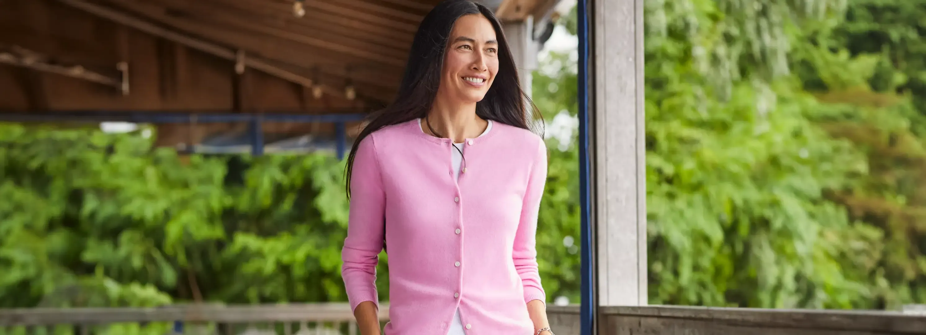 Woman wearing a pink cardigan and white tee standing outdoors.