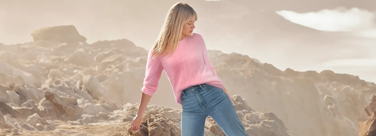 Woman wearing a pink sweater and blue jeans.