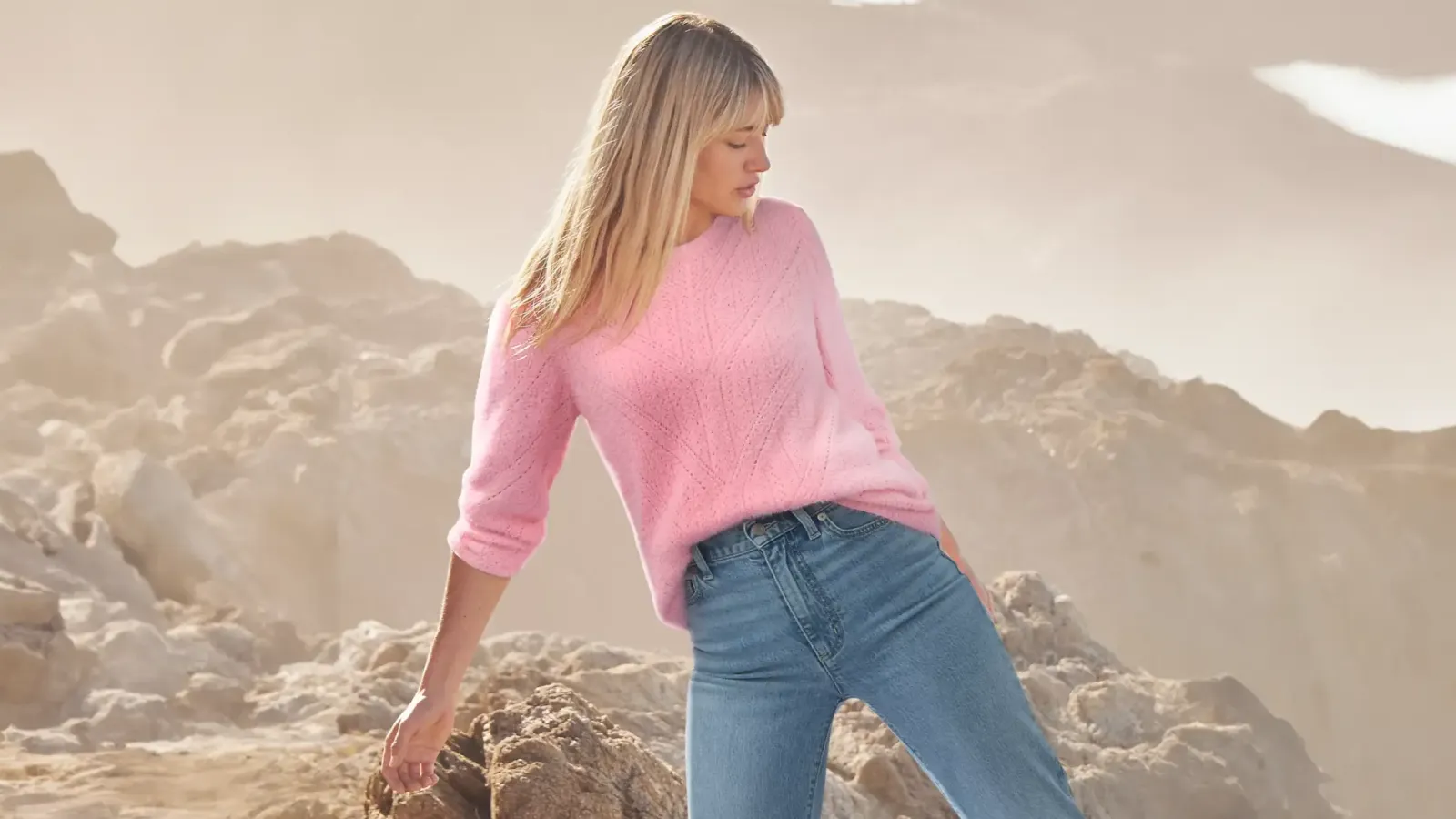 Woman wearing a pink sweater and blue jeans.
