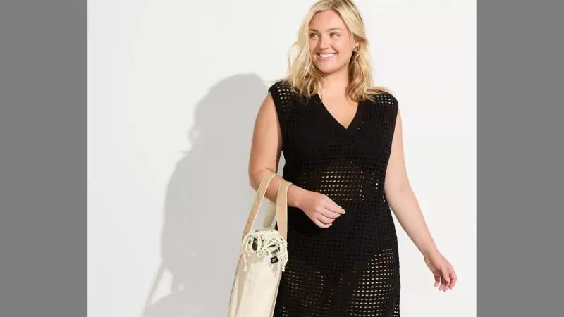 Woman wearing a plus size swim cover-up carrying a tote bag.