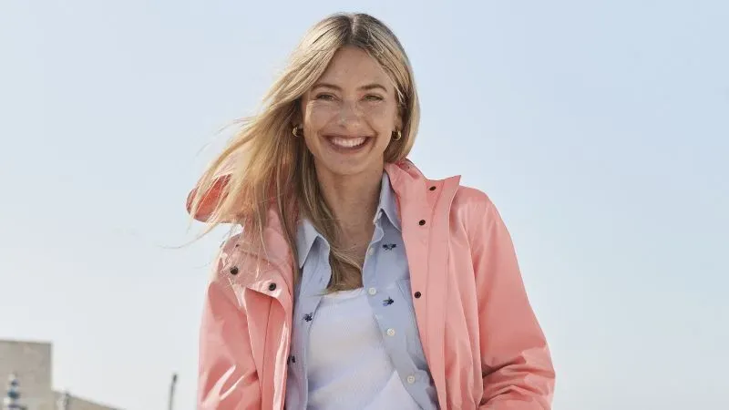 Woman wearing coral colored spring coat over a light blue button-down shirt and white cotton tee shirt.
