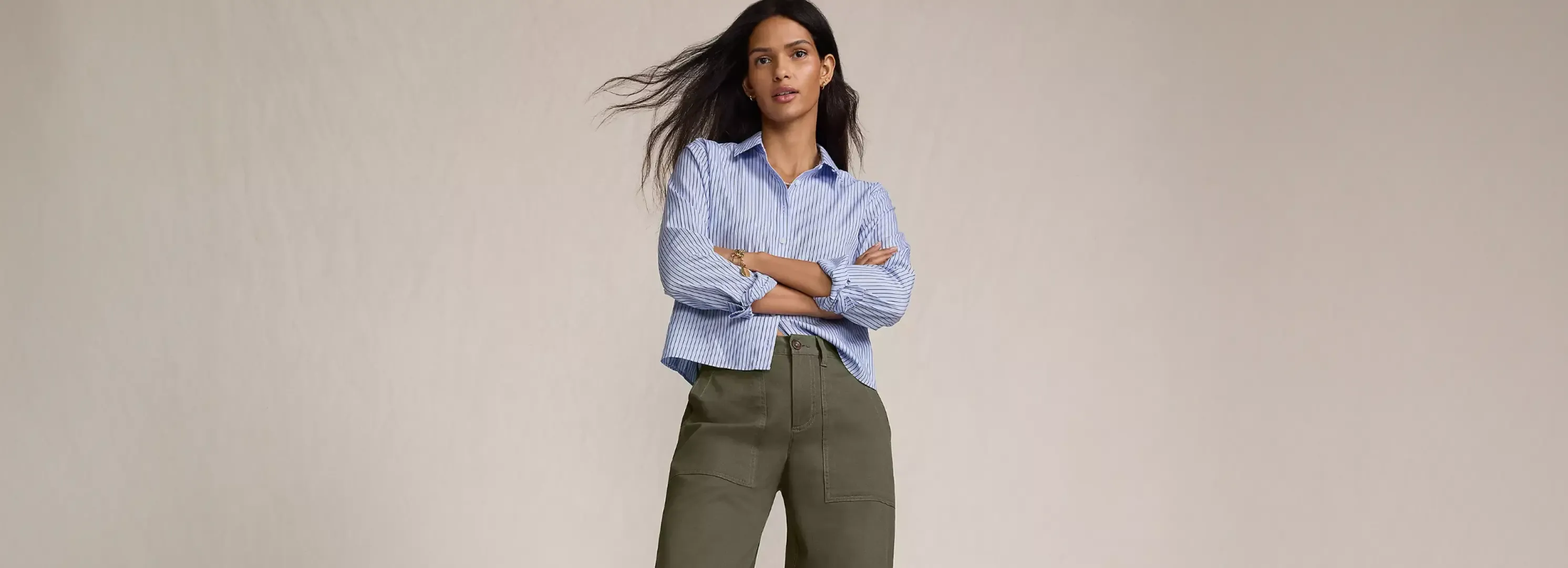 Woman in a blue striped dress shirt and olive pants.