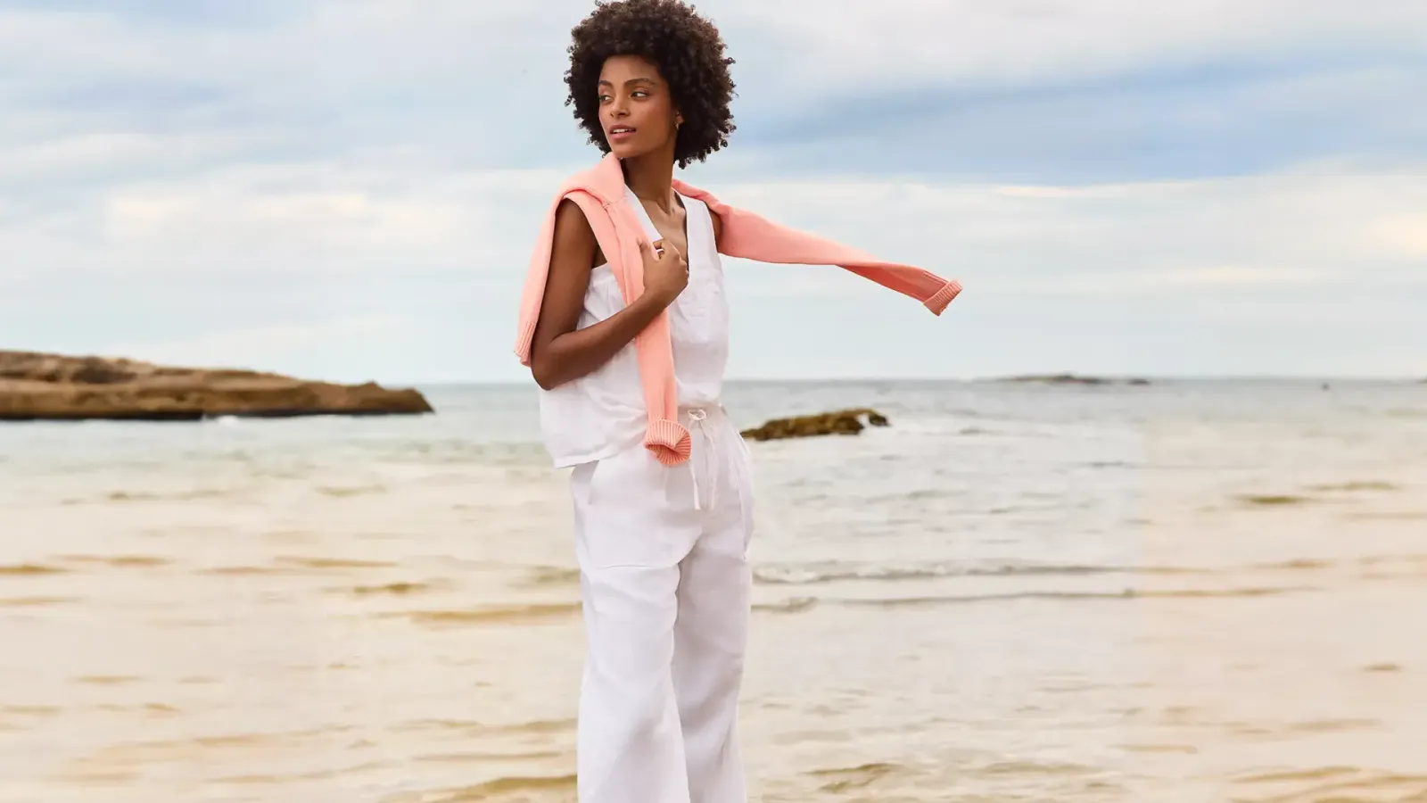 Woman wearing White Linen Pants, Tank Top and Pink Sweater.