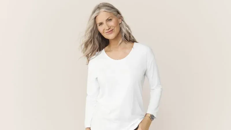 Woman wearing a white long sleeve scoop neck t-shirt.