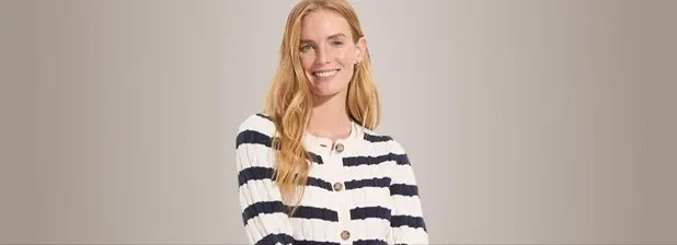 Woman wearing a white and navy blue striped ribbed button-front cardigan.
