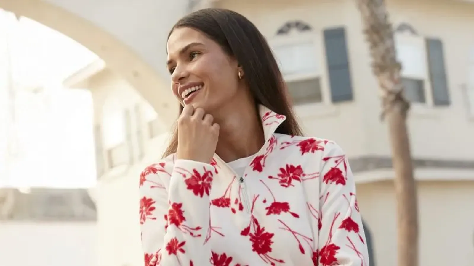 Woman wearing a white fleece with red floral print pattern.