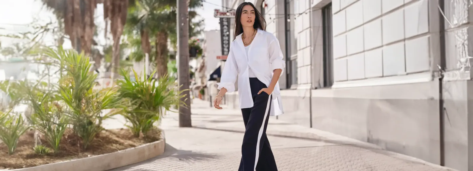 Woman wearing a white shirt and navy pants.
