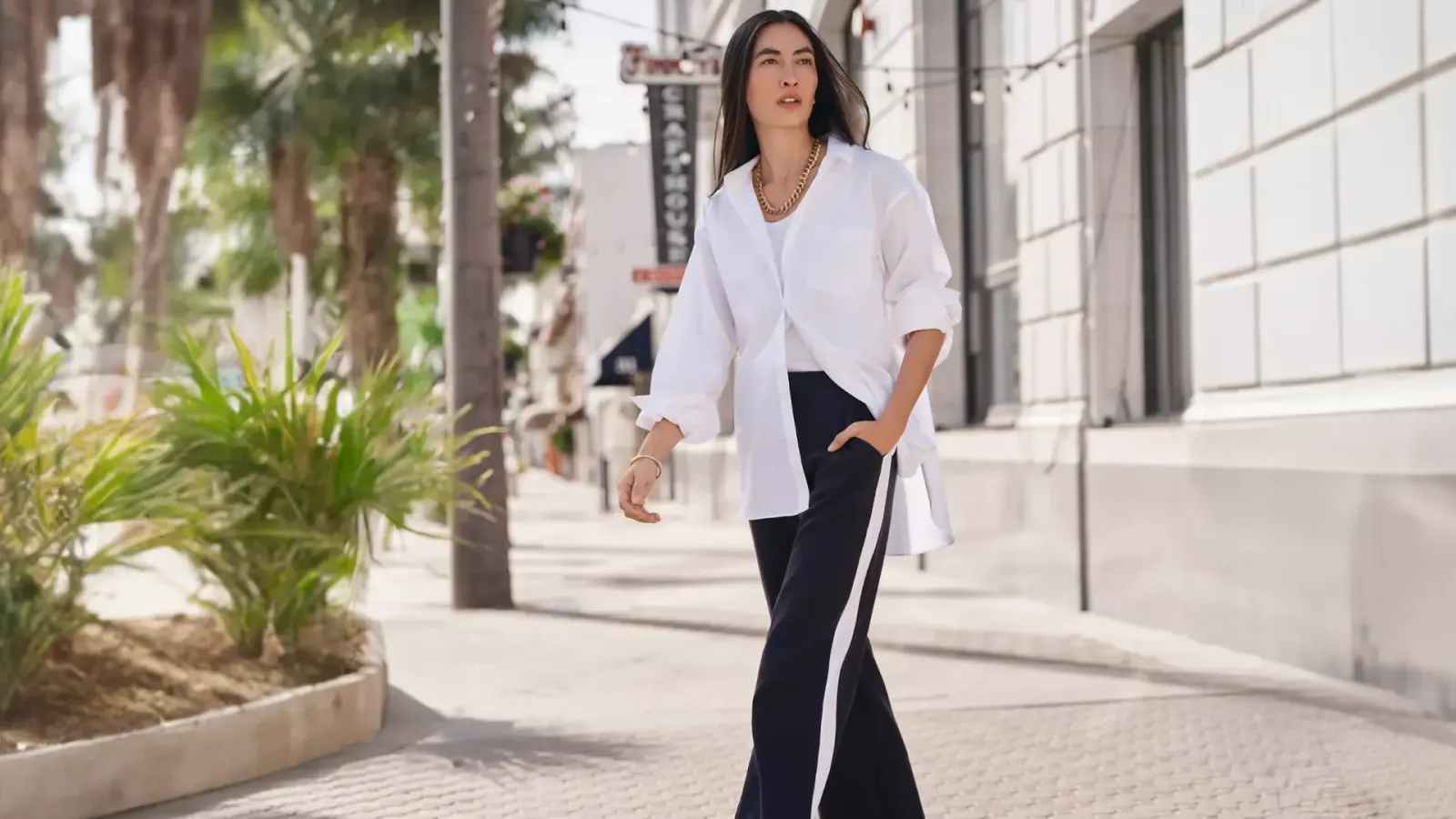 Woman wearing a white shirt and navy pants.