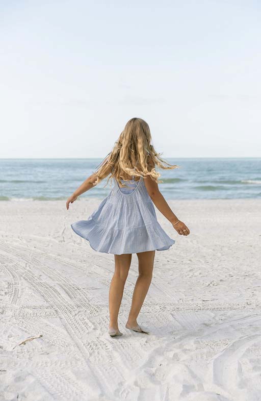 A woman wearing a cover up dress on the beach.