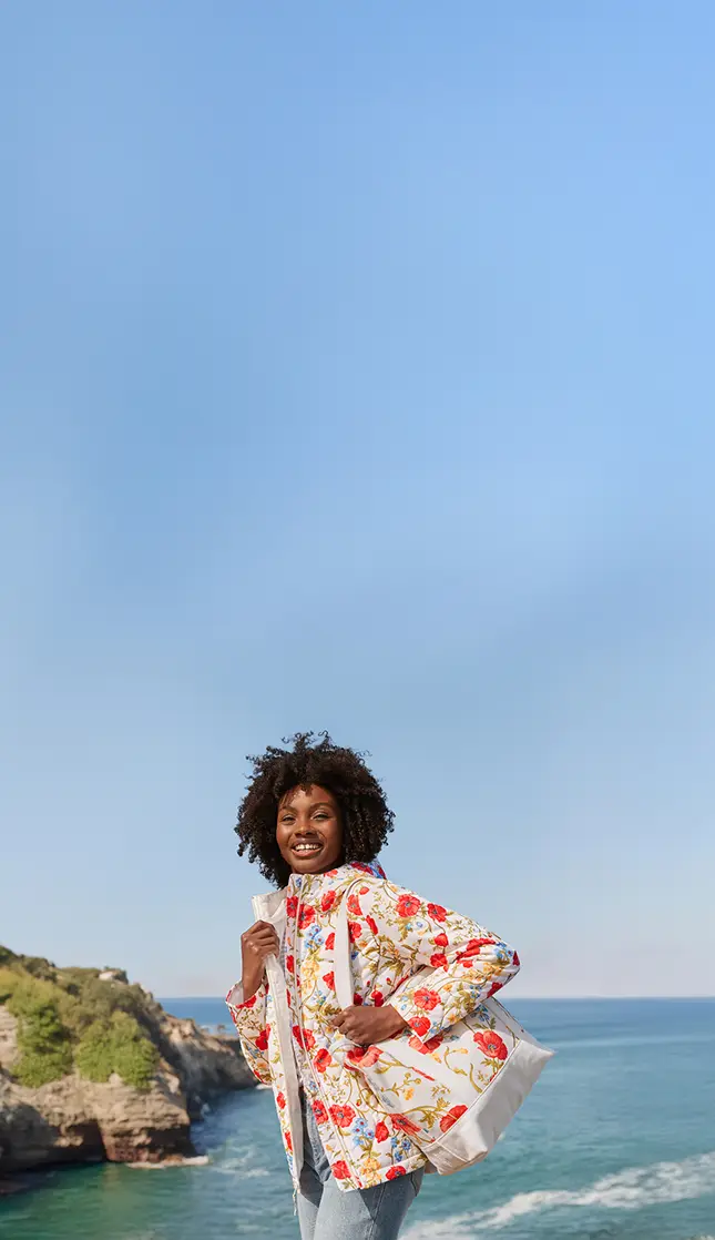 A woman wearing a floral patterned coat and tote.