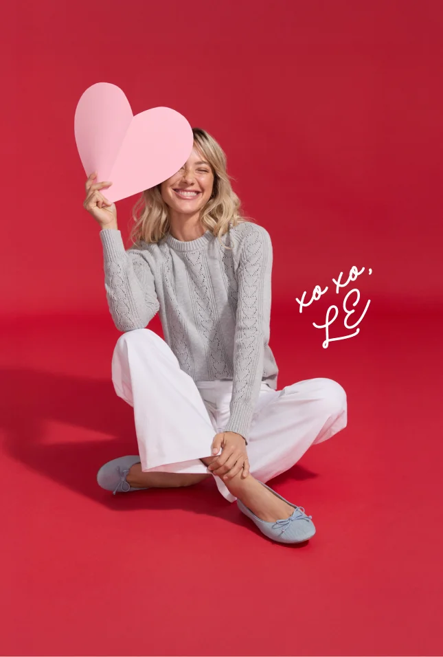 Women holding paper hearts and wearing sweaters, shoes and pants