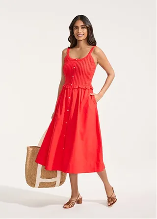 A woman wearing a red dress and holding a tote.