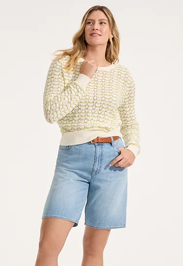 A woman wearing a cream top and denim shorts.