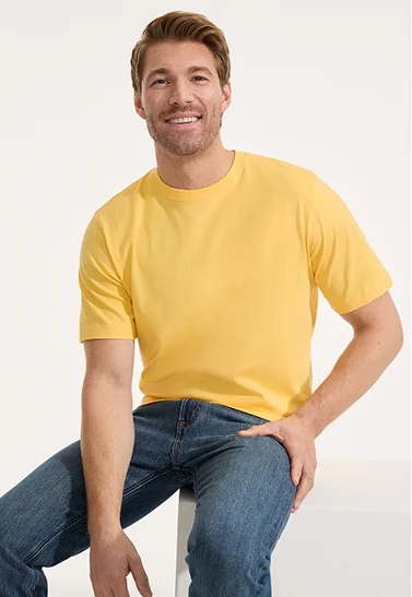 A man wearing a yellow t-shirt and blue jeans.