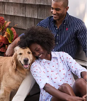 A man wearing a navy button down with white stripes and a woman wearing a white button down shirt with a repeating cherry pattern.