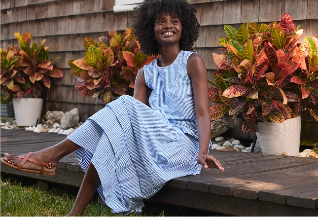 Woman wearing a blue and white striped seersucker midi skirt.