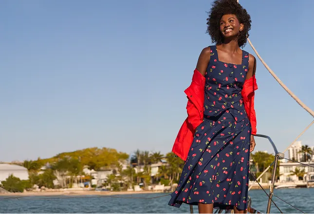 Woman wearing a navy dress with a repeating cherry pattern.