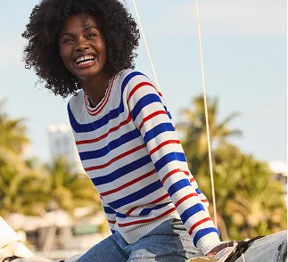 A woman wearing a white sweater with horizontal blue and orange stripes.