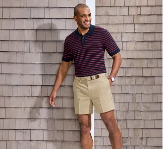 A man wearing a red and black striped polo with khaki shorts.